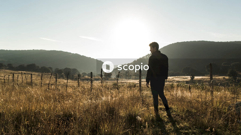 Back view of young man in leather jacket standing on brown field