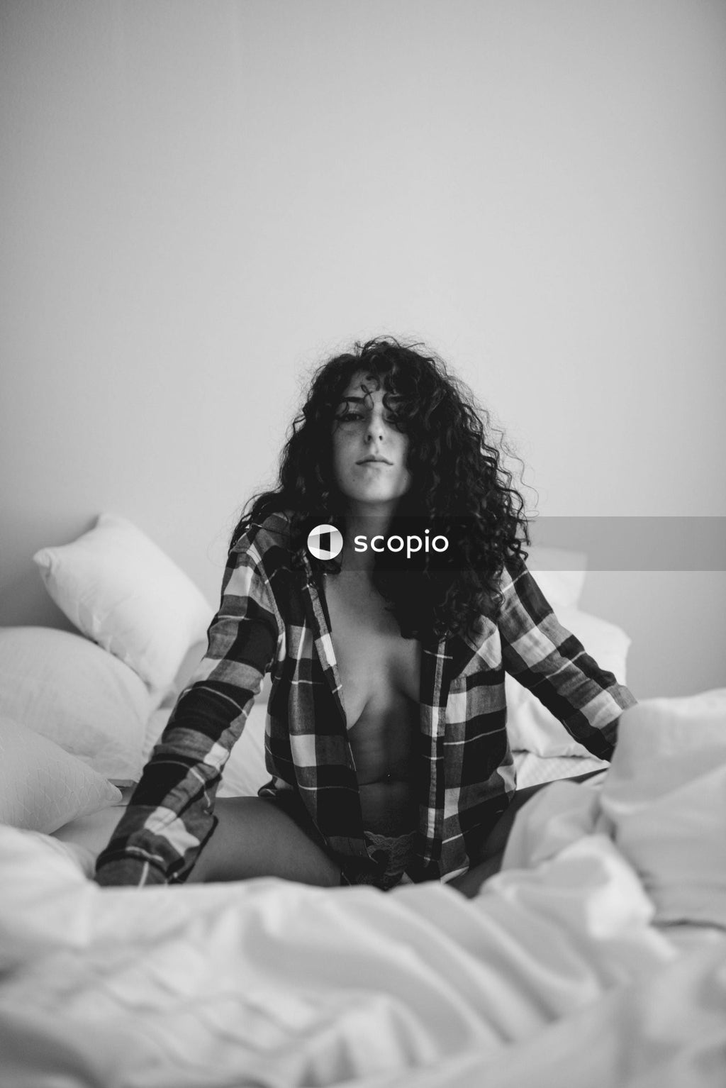 Woman in plaid dress shirt sitting on bed