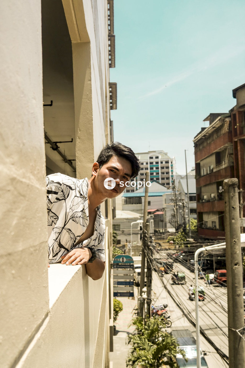 Man in white and black floral button up shirt looking from window