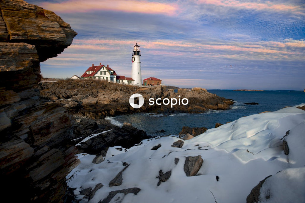 White and red lighthouse on brown rock formation near body of water