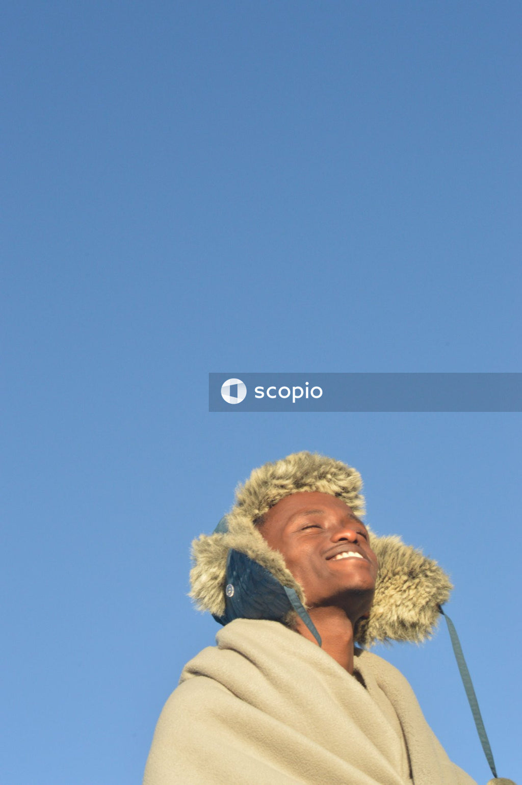 Black Man Wearing hat with blanket standing under blue sky