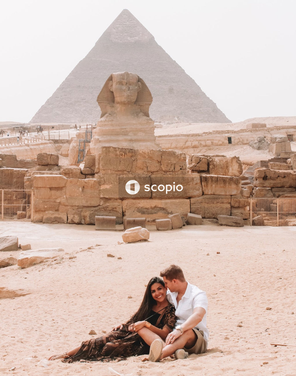 Couple relaxing on sand in front of giza pyramids, egypt