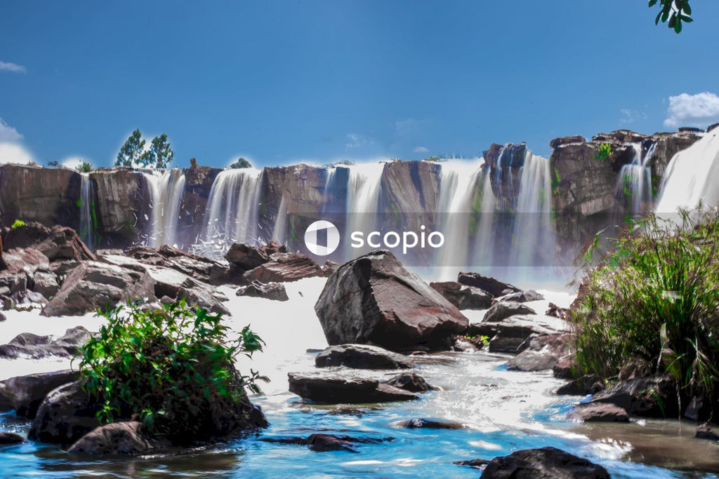 Waterfalls near green plants under blue sky