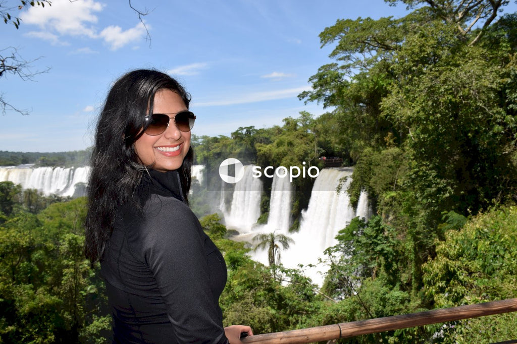 Woman in black long sleeve shirt wearing black sunglasses standing near waterfalls
