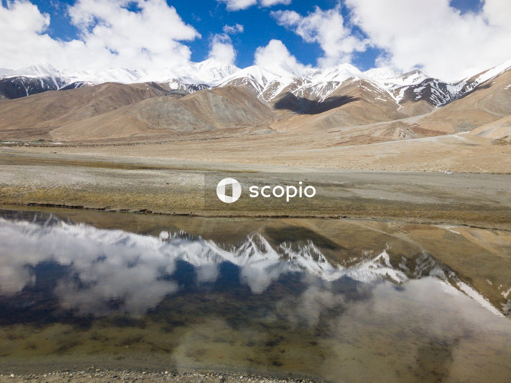 Brown and white mountains near body of water under blue sky