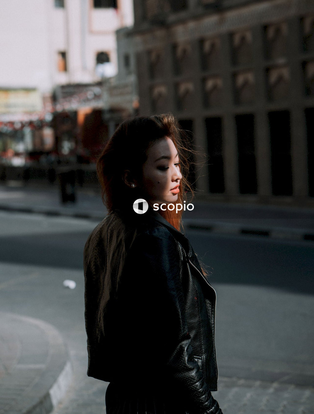 Woman in black leather jacket standing on road