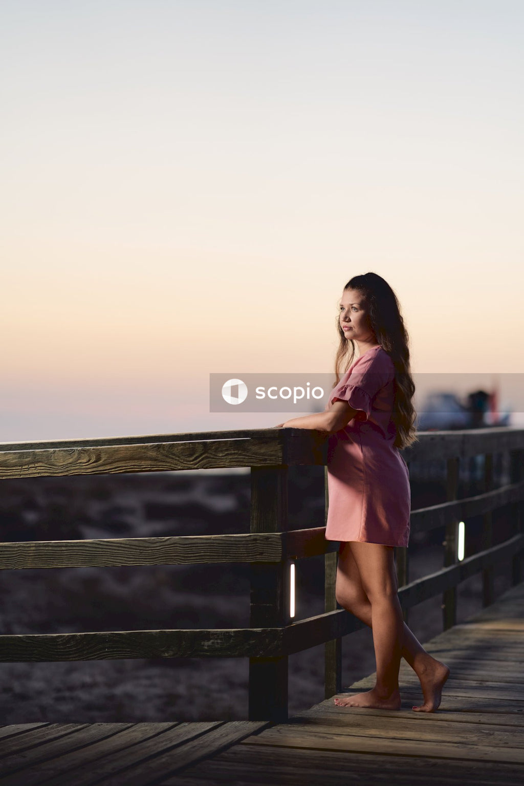 Woman in pink dress standing at the terrace during sunset