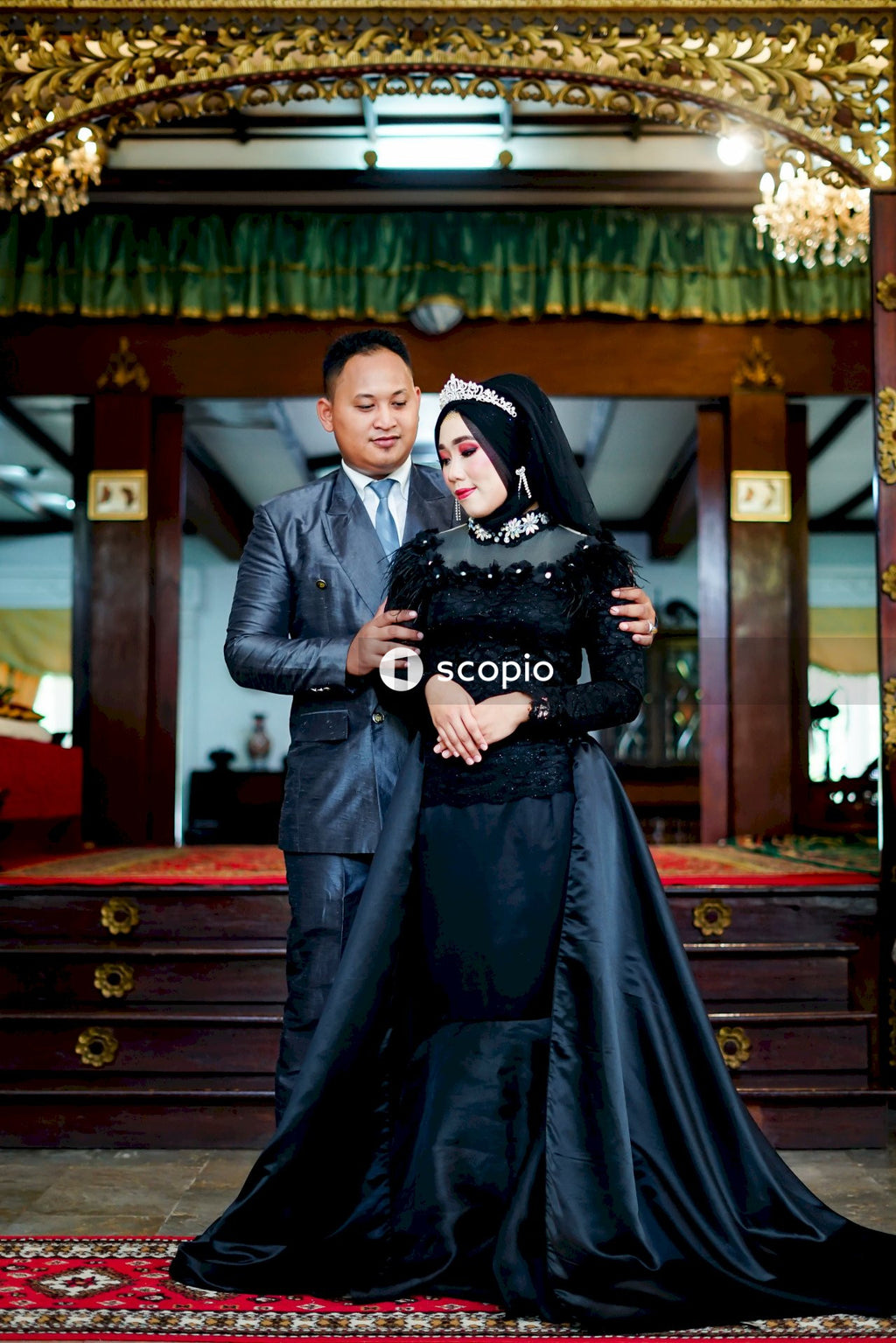 Man in black leather jacket hugging woman in black dress