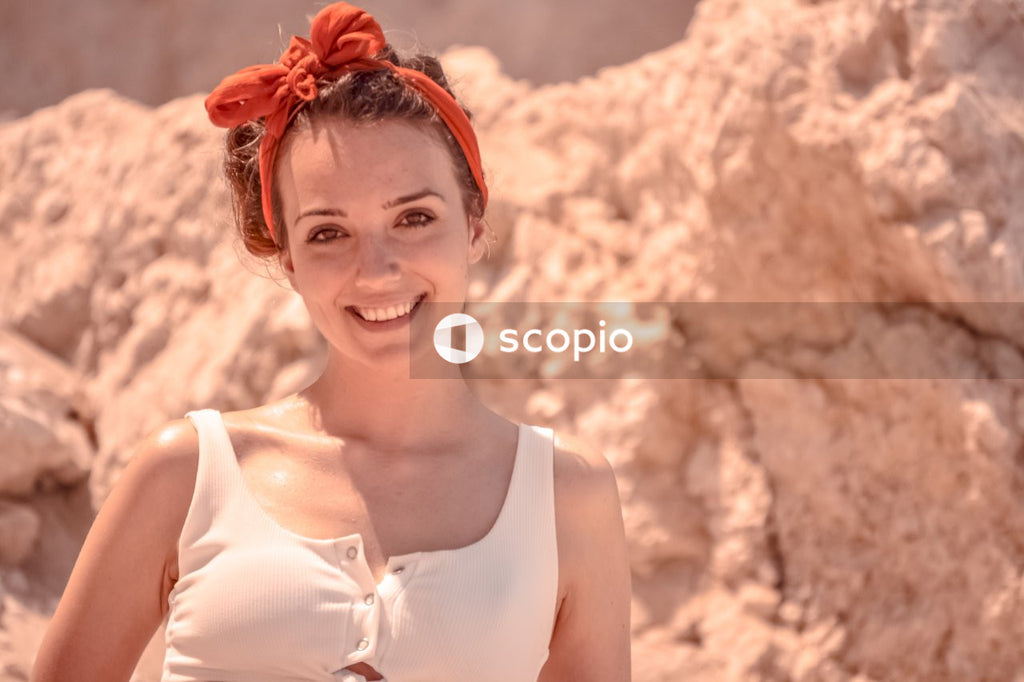 Smiling woman in white tank top wearing red flower headband