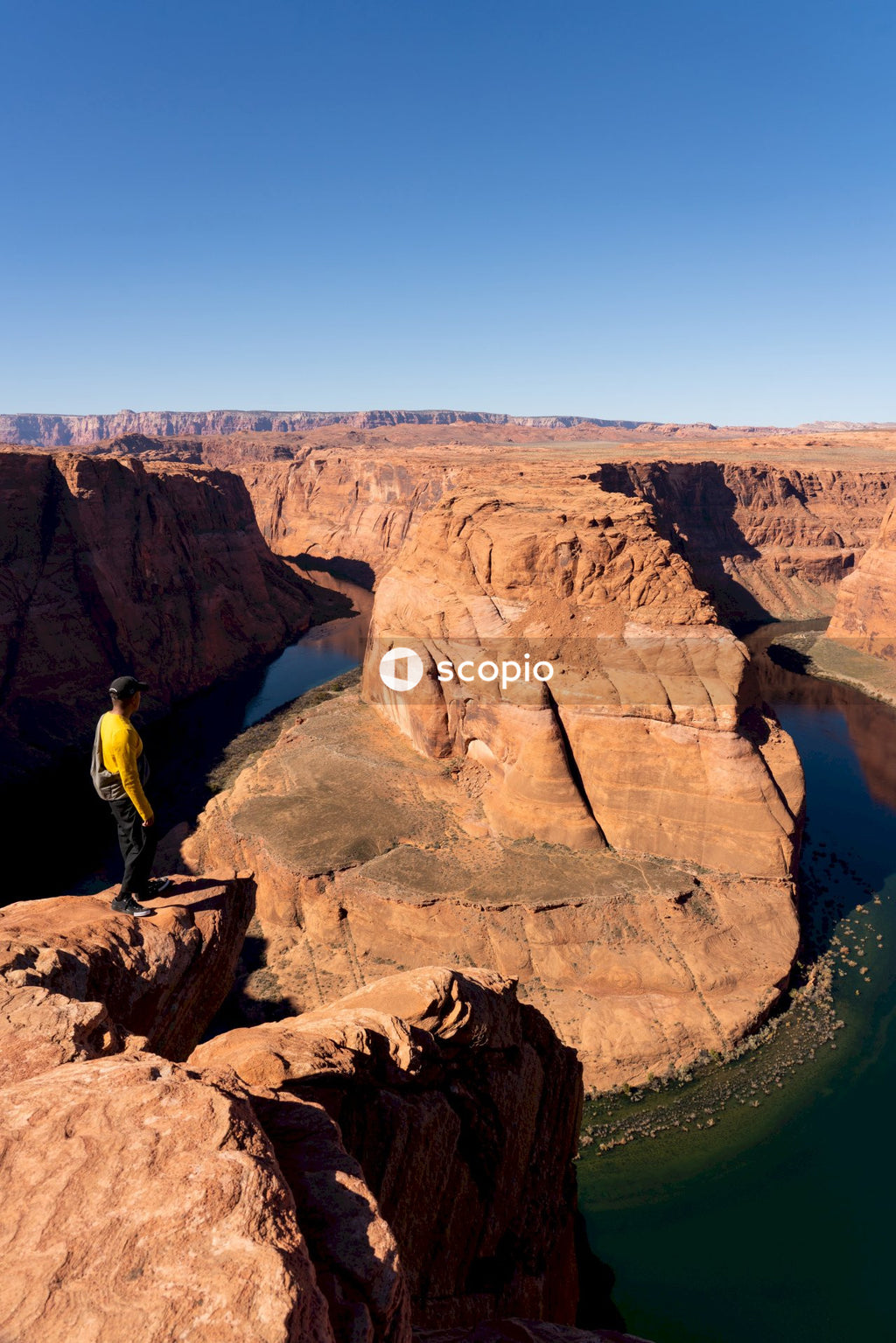 Man in yellow shirt and black pants climbing on brown rock formation