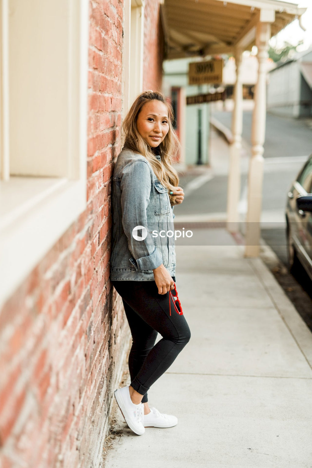 Side view of woman in denim jacket leaning on a wall