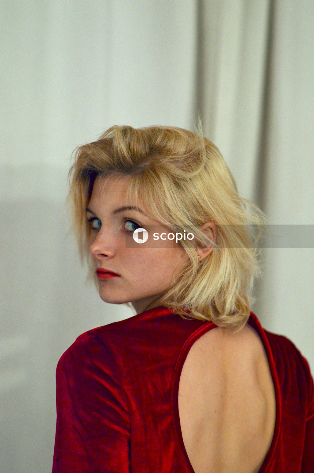 Woman wearing red dress near white curtain