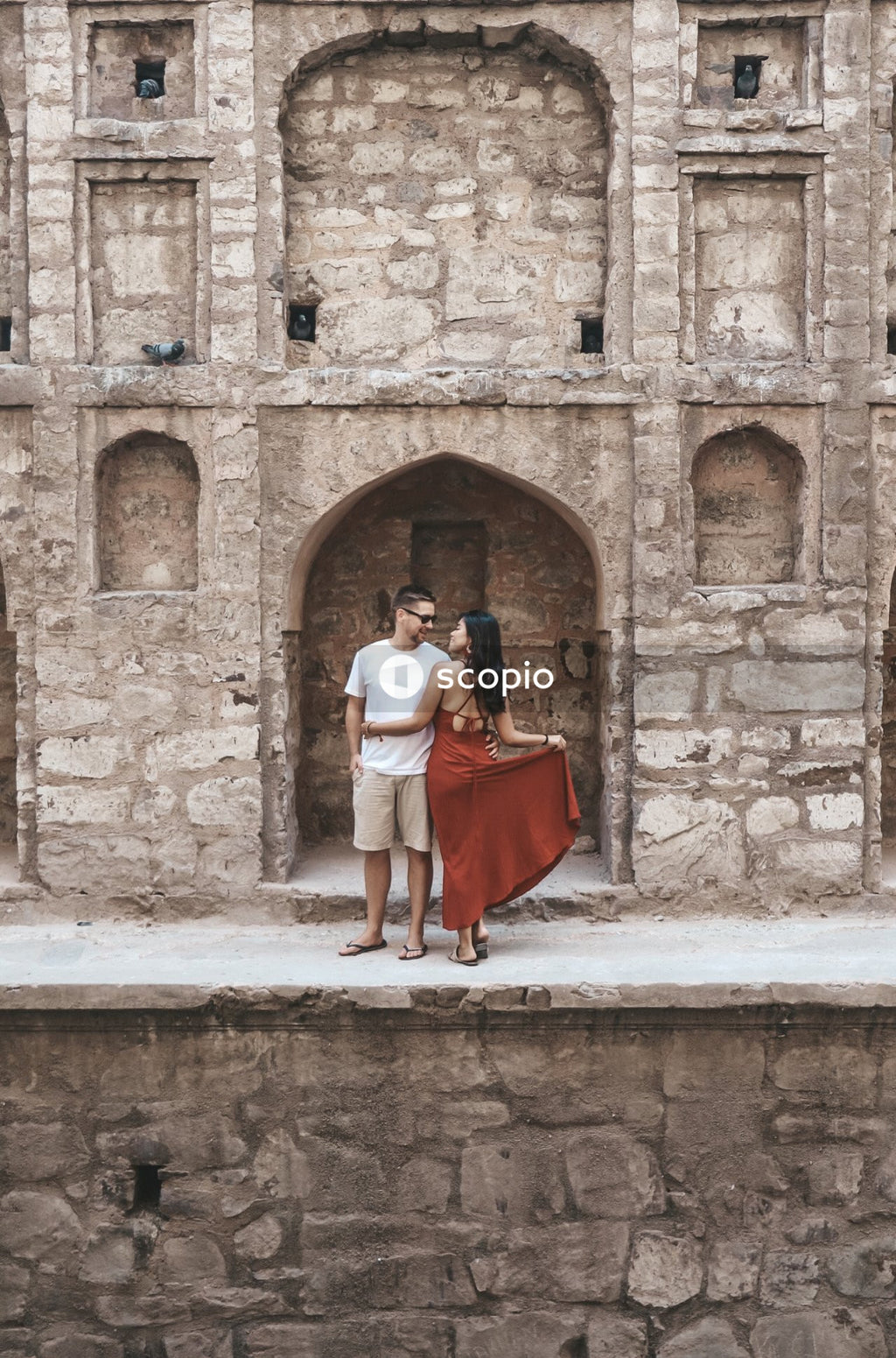 Woman in red dress hugging a man in Agrasen Ki Baoli historical step well in New Delhi, India