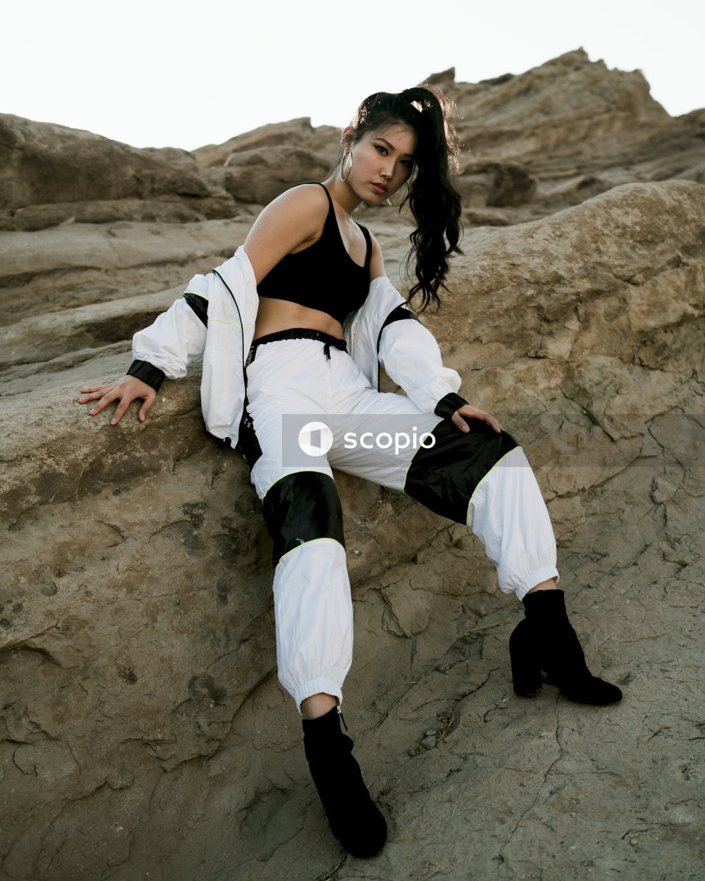 Woman in light and dark outfit posing on rock outside