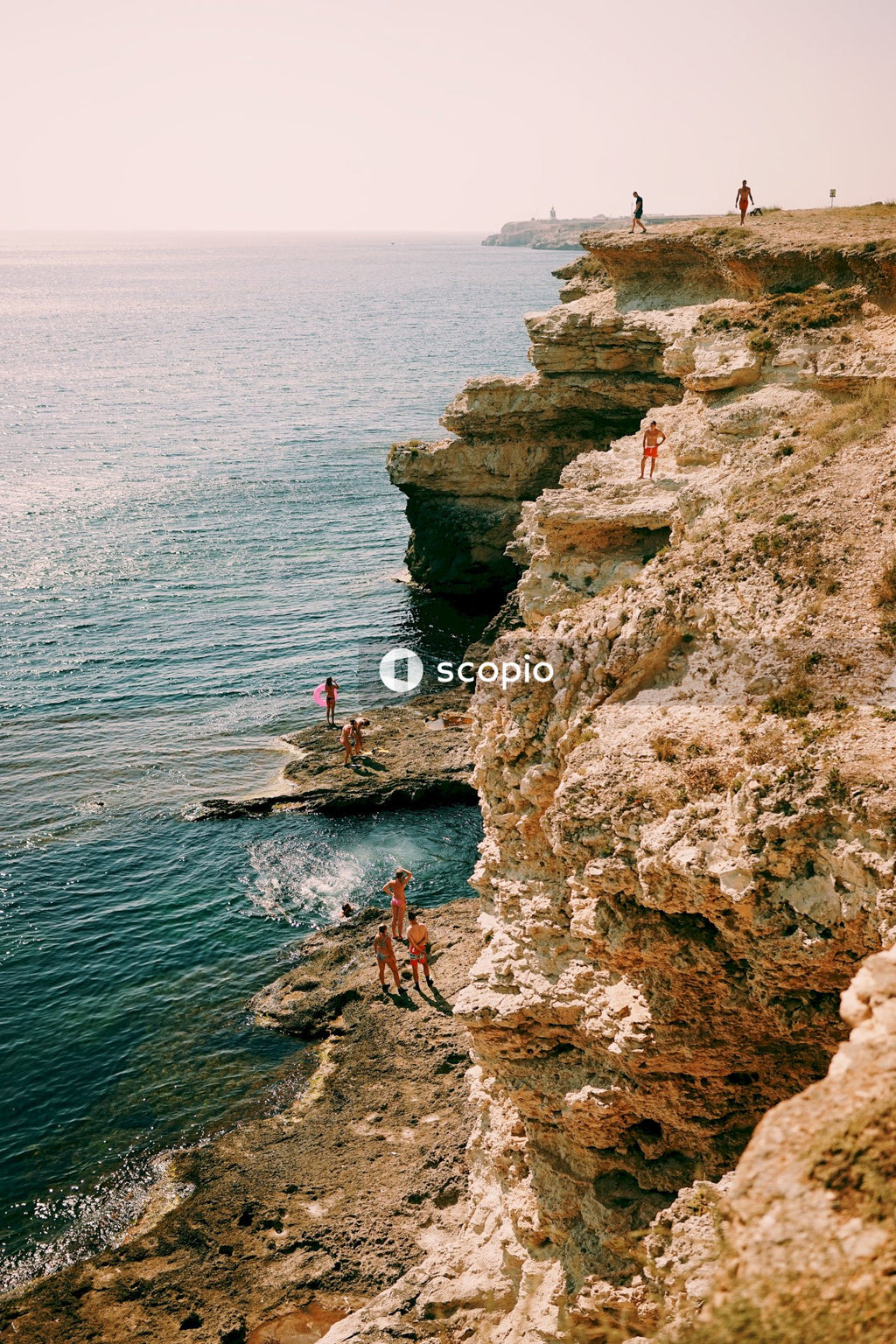 Person in red shirt standing on rock formation near body of water