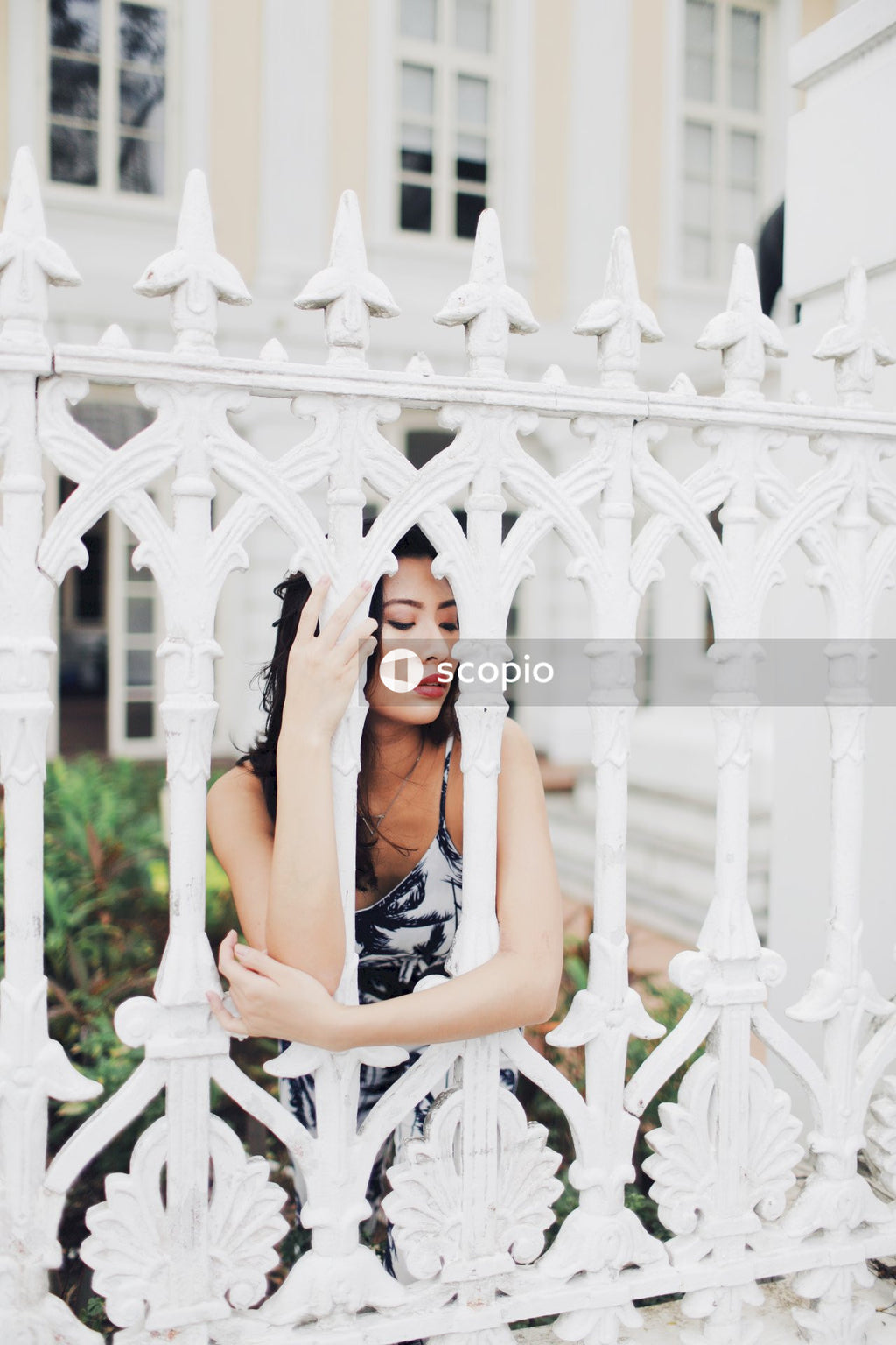 Woman in light and dark jumpsuit behind light building fence