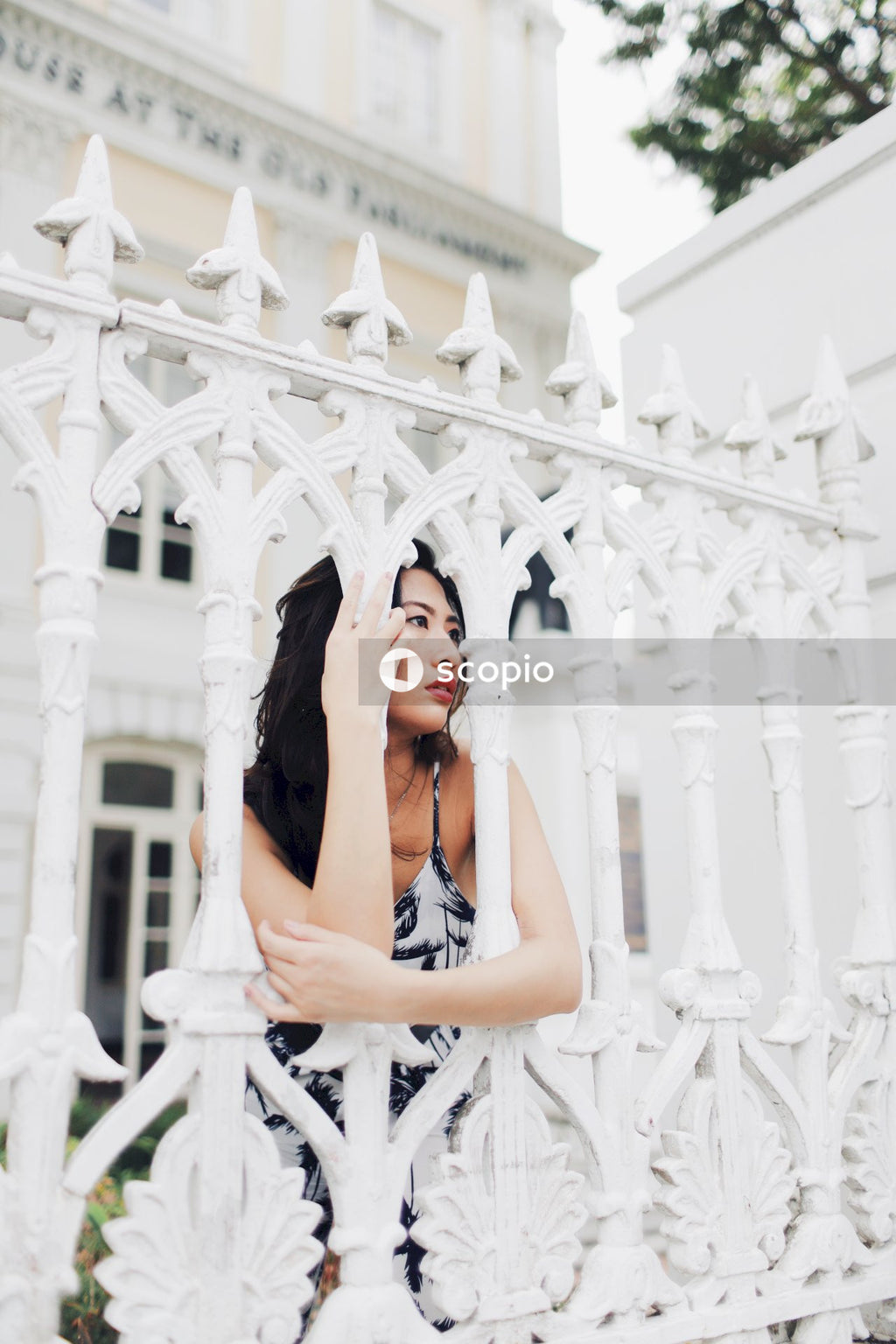 Woman in light and dark jumpsuit behind light building fence