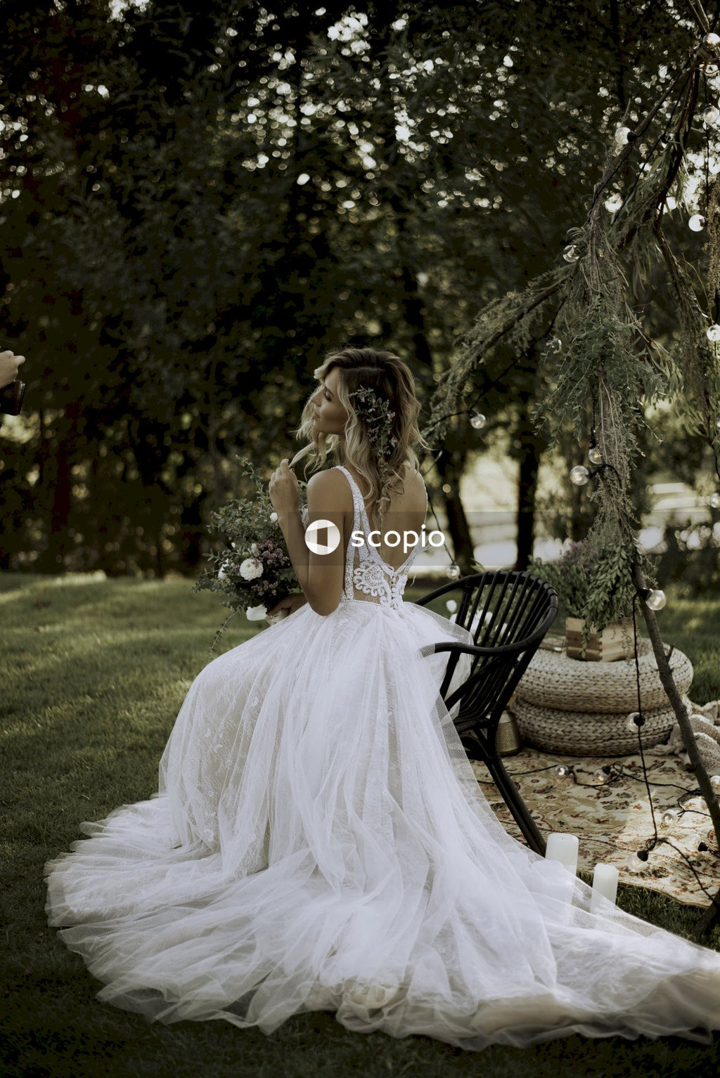 Back view of woman in wedding dress sitting on chair in the woods