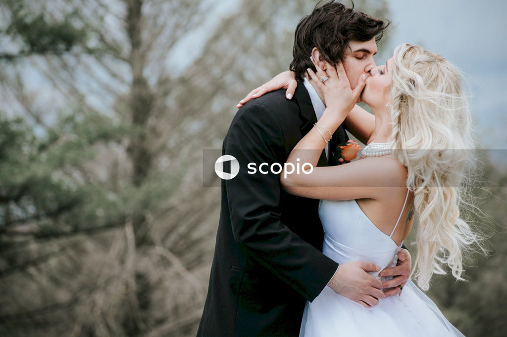 Man in black suit kissing woman in white dress