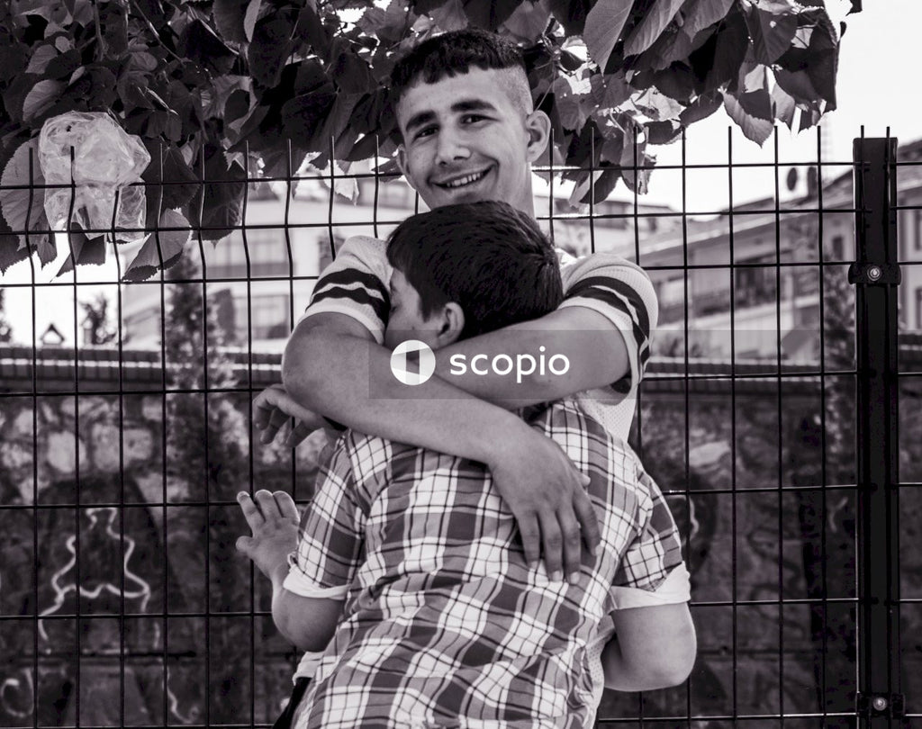 Man in plaid shirt hugging woman in grayscale
