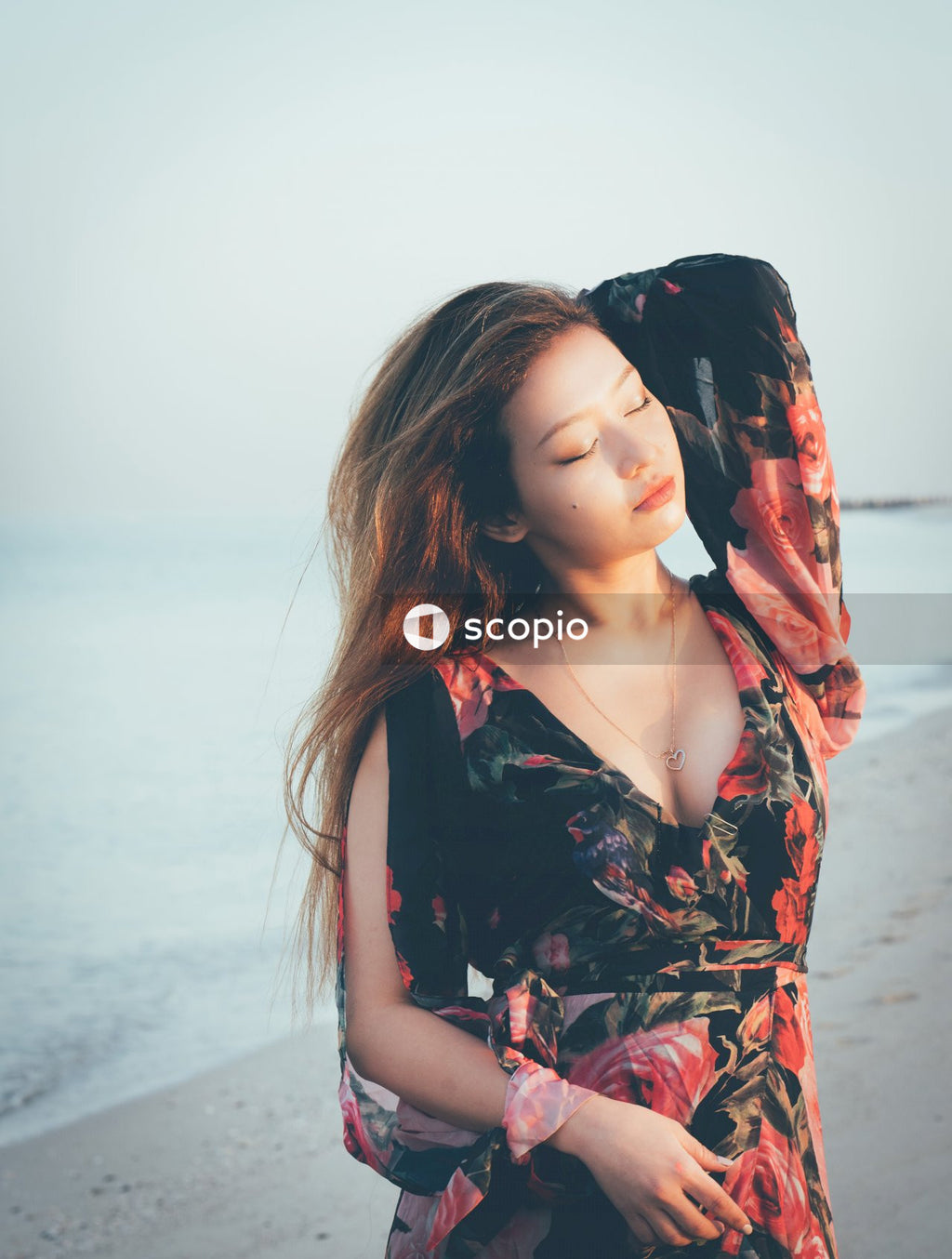 Woman in red floral dress standing on beach