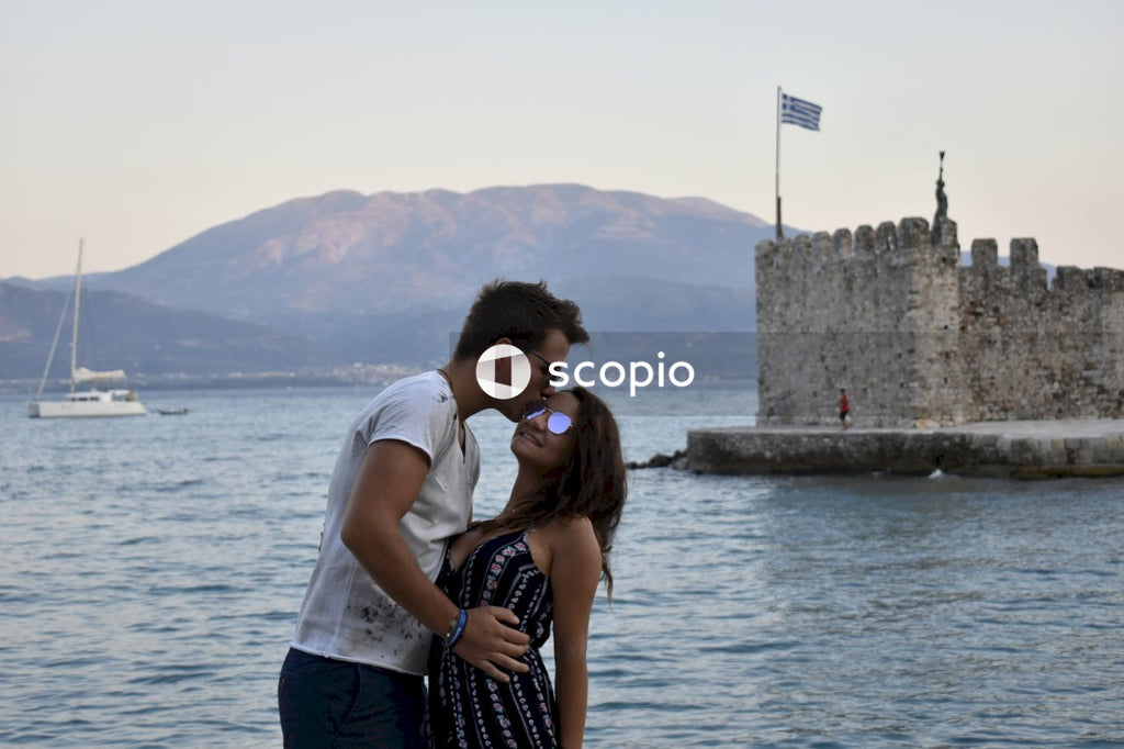 Couple kissing on concrete wall near body of water