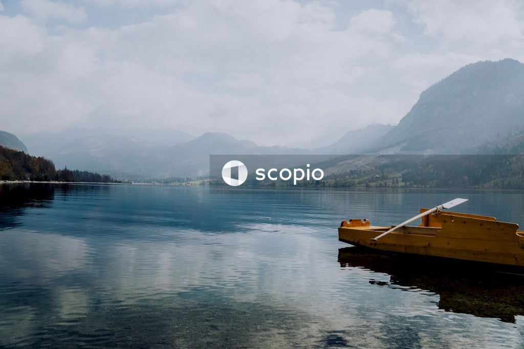 Yellow Boat on Calm Lake With Mountains and Clouds.
