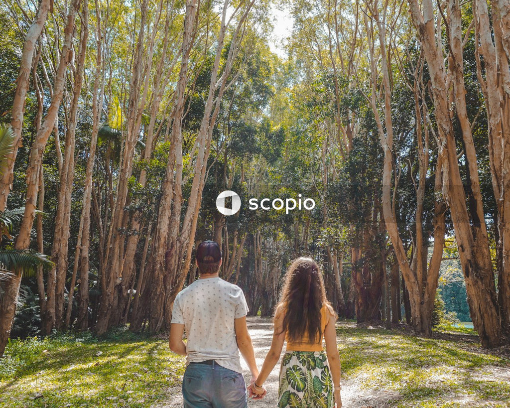 Man and woman walking on green grass field surrounded by trees