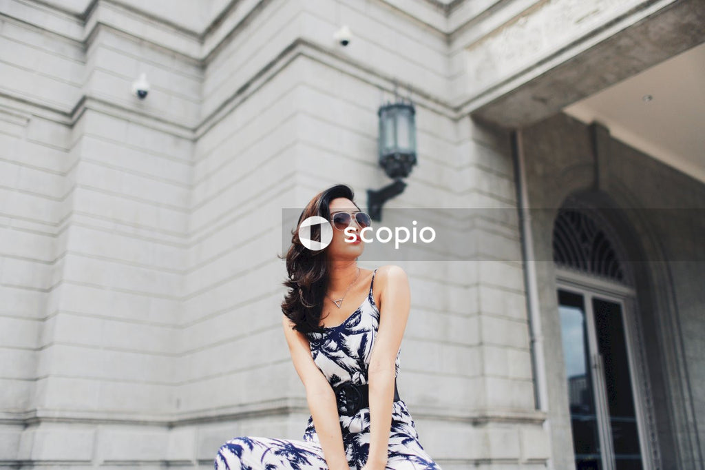 Woman in light and dark jumpsuit posing in front of building