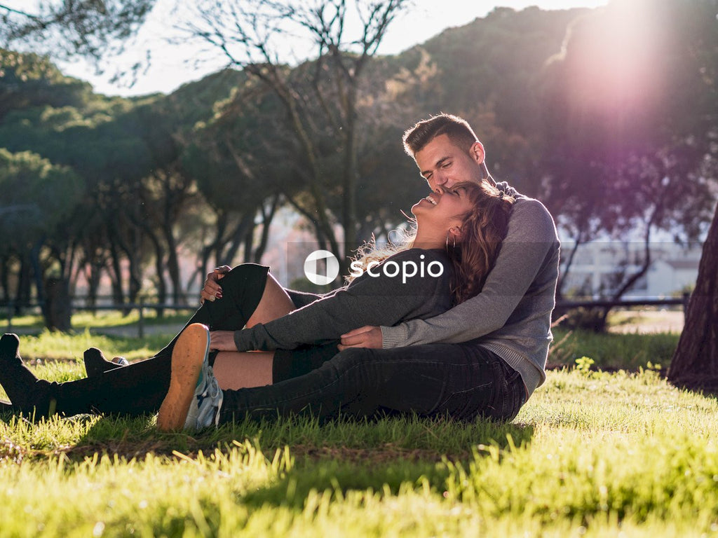 Woman in brown long sleeve shirt and black pants sitting on green grass field