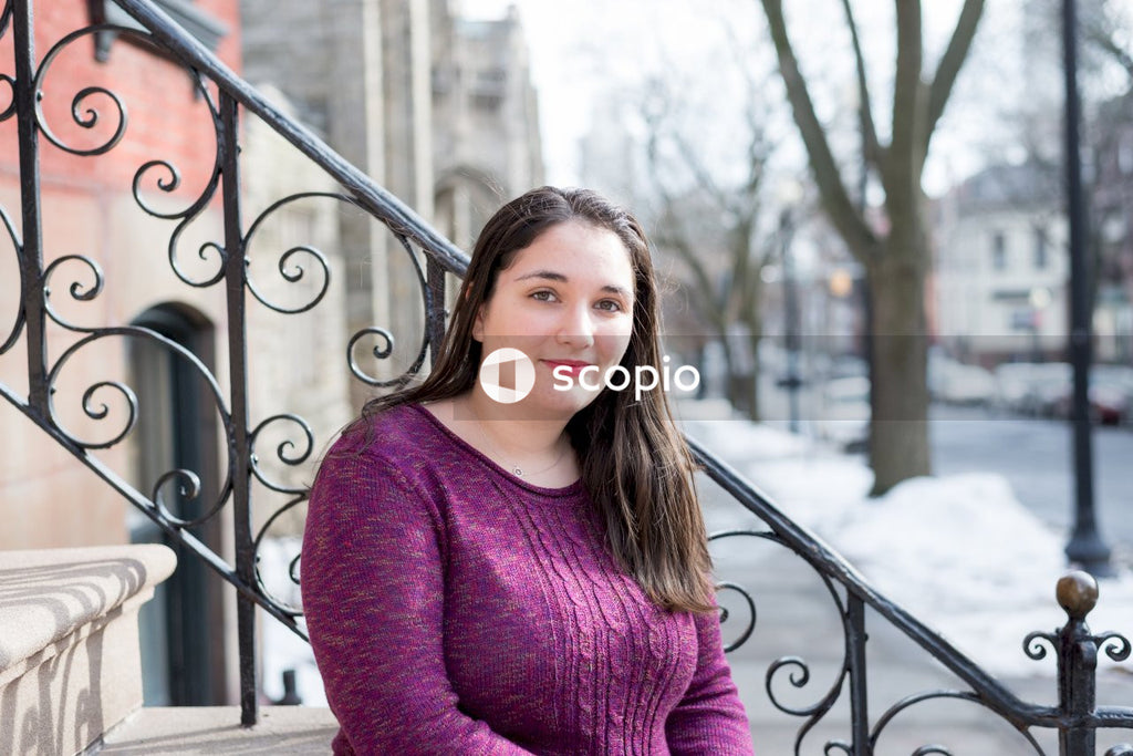 Woman in maroon long sleeve shirt standing beside black metal fence