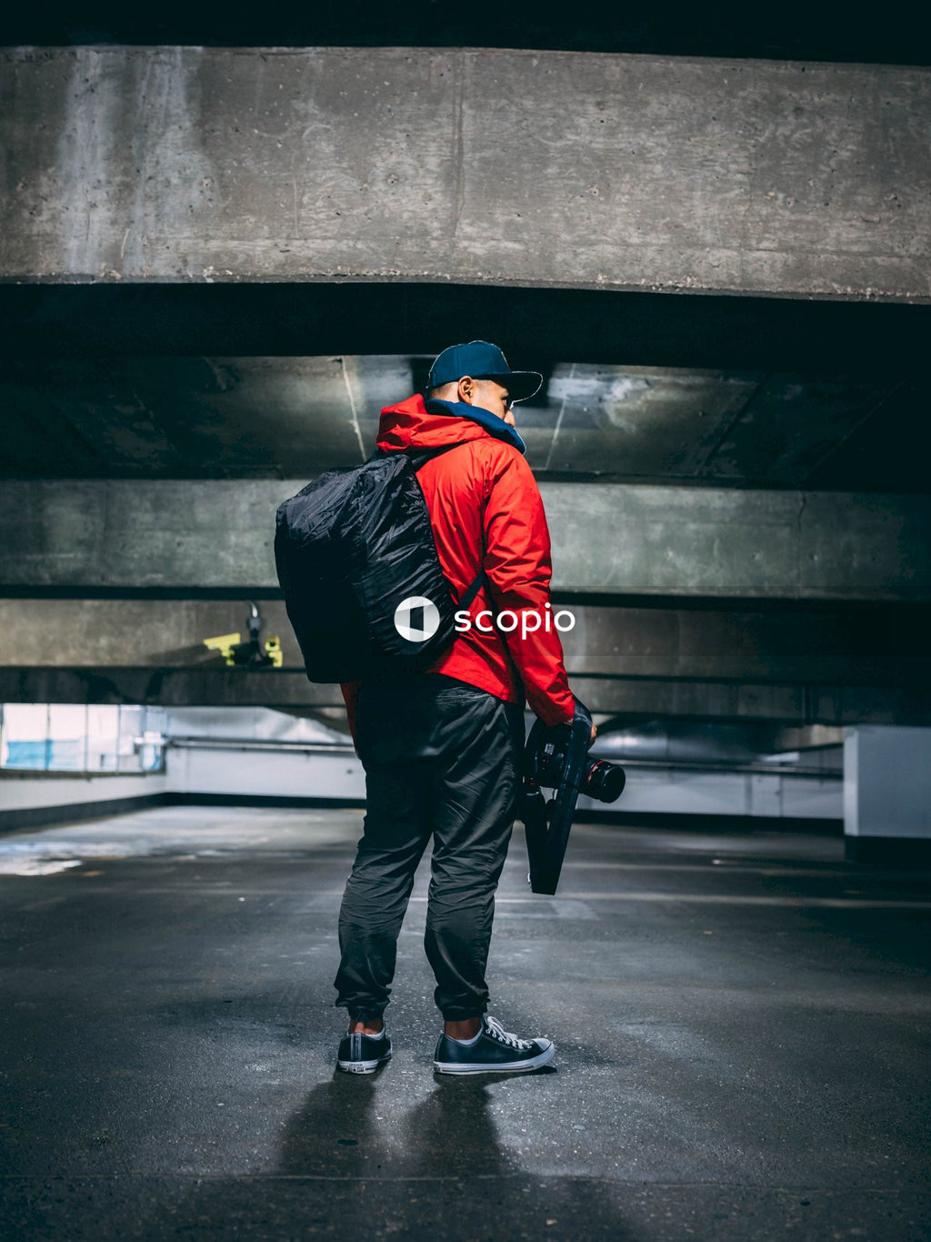 Man in red jacket standing holding camera standing in parking lot