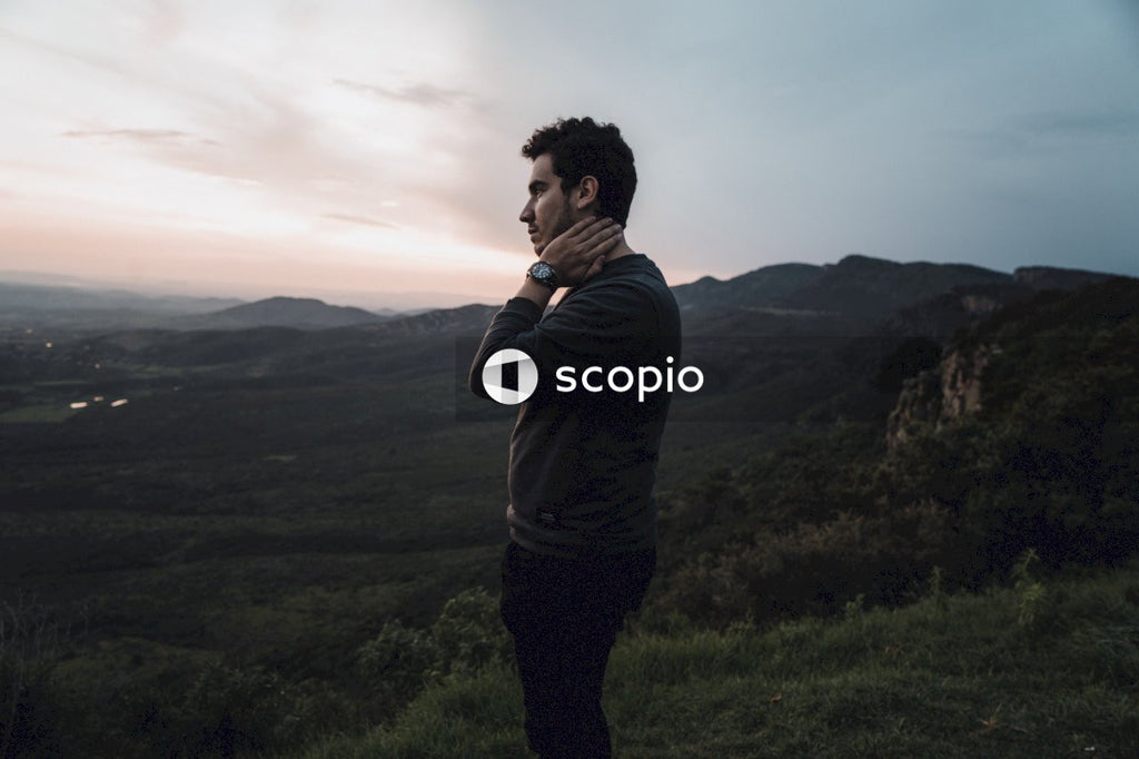 Man in gray shirt standing against mountainous landform at sunset