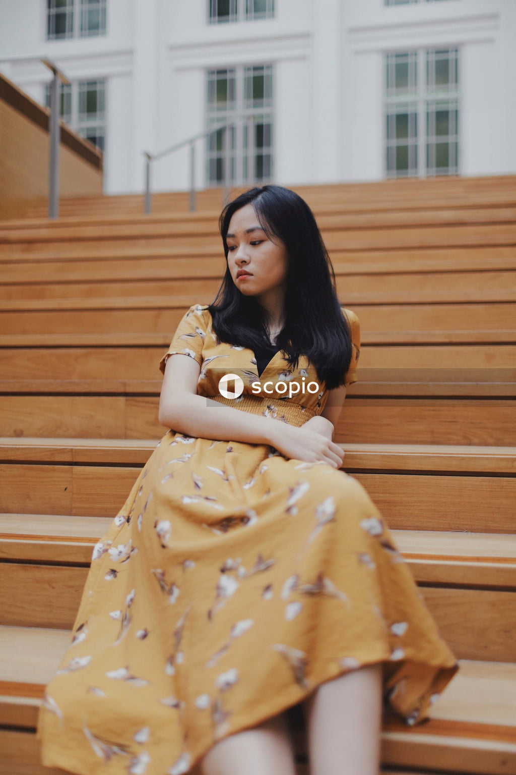 Woman in orange dress sitting on brown stairs