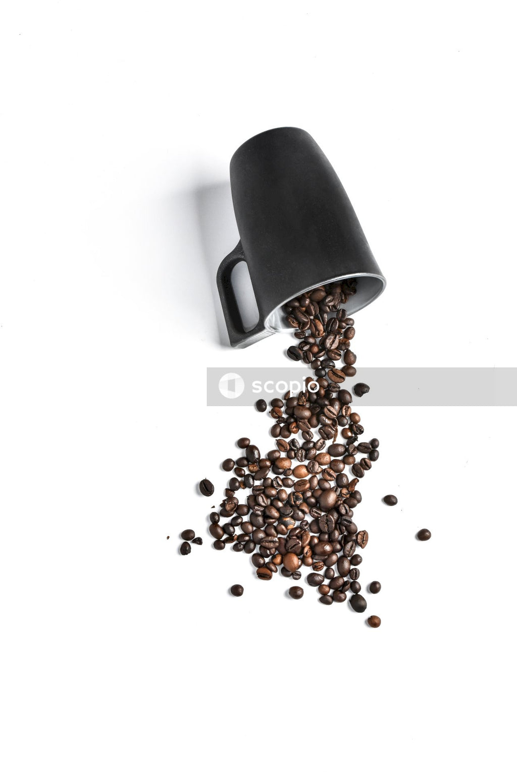 Coffee Beans Escape From Black Mug That Lies on White Background
