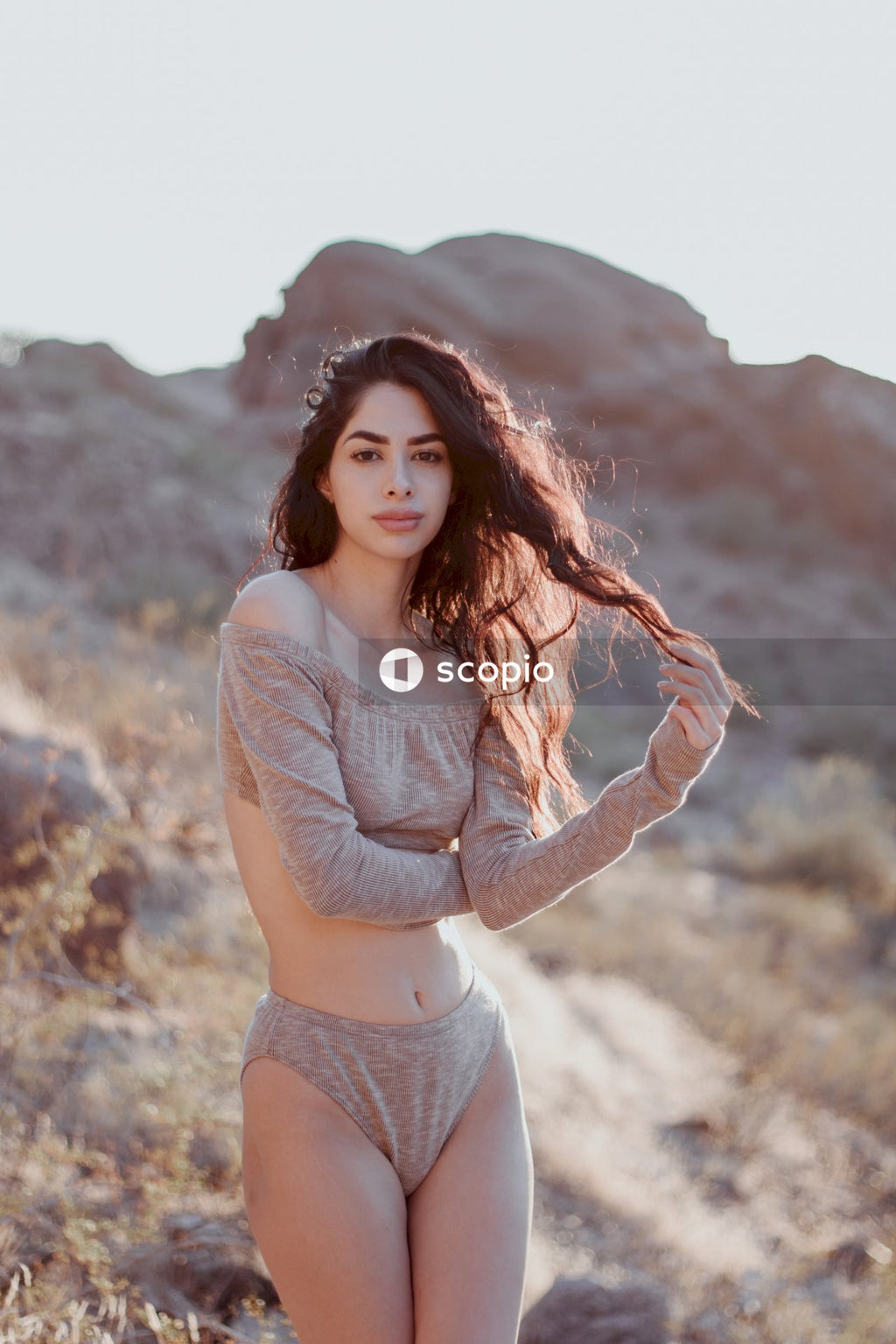 Woman in gray long sleeve shirt standing on brown field