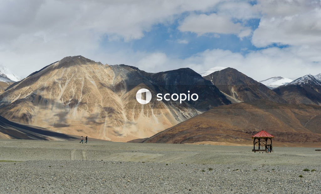 People walking on gray sand near brown mountain