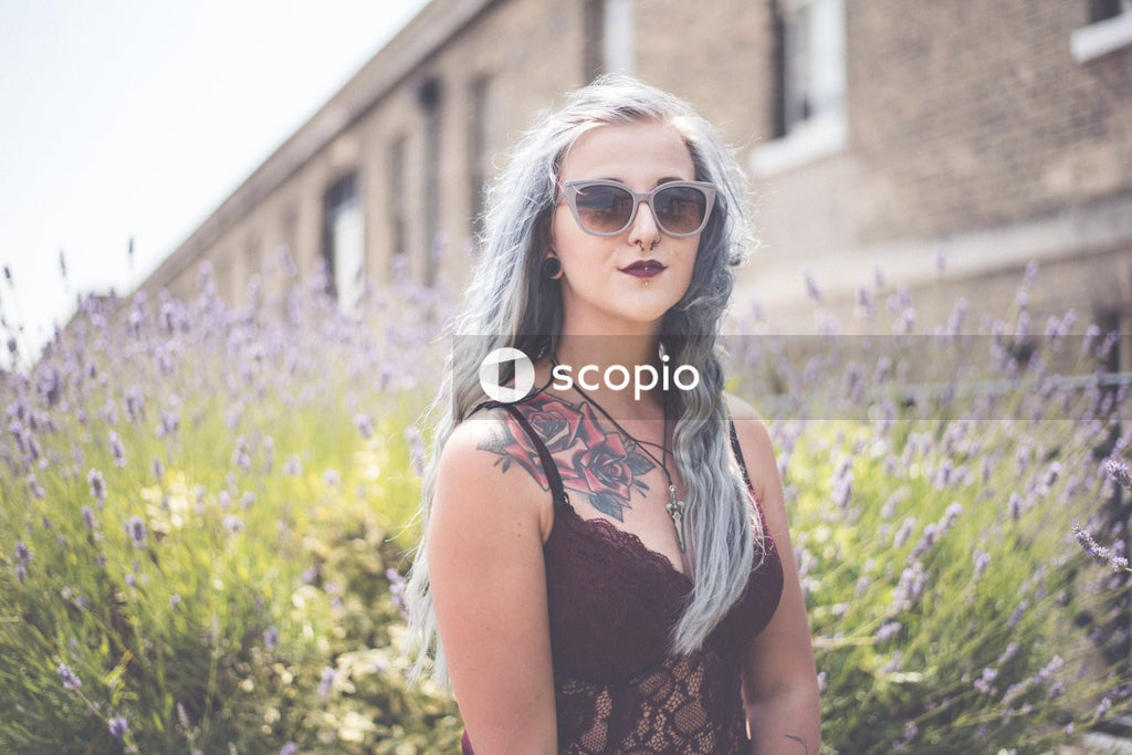 Woman in red bra wearing sunglasses standing in purple flower field