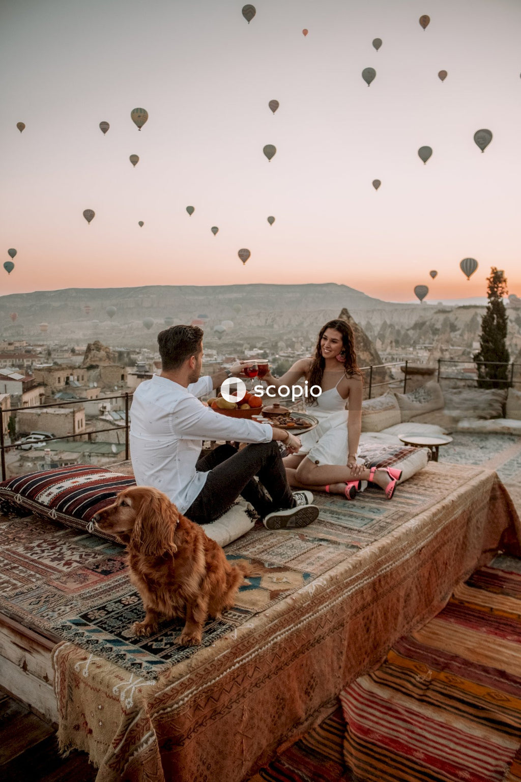 Man and woman raising toast on rooftop with hot air balloons in sky