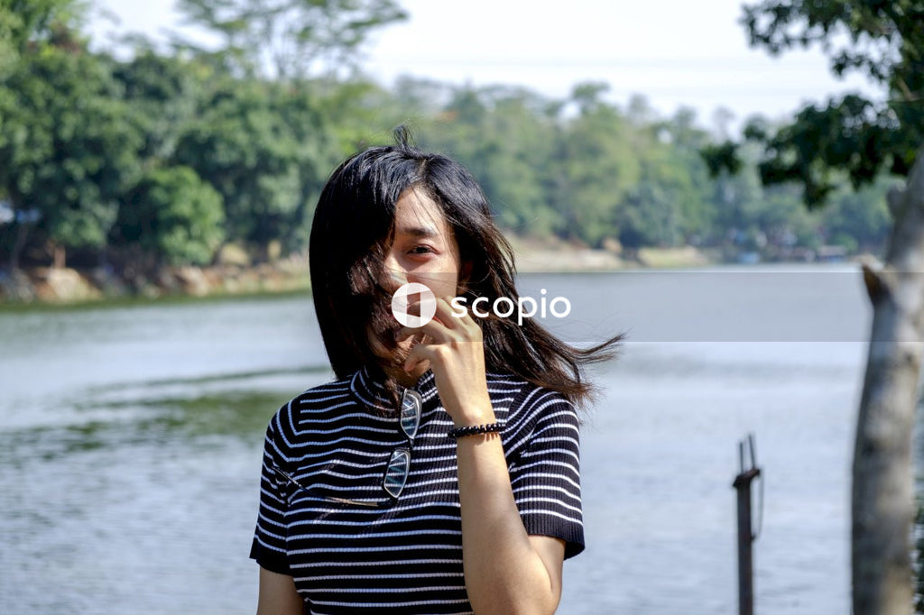 Woman in black and white stripe shirt standing near body of water