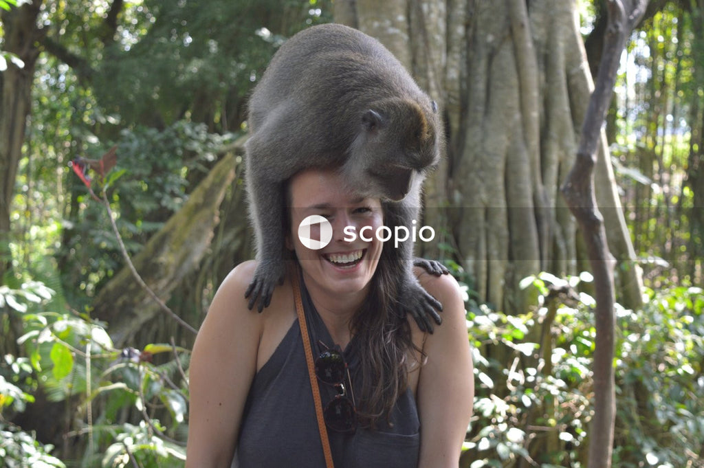 Woman in tank top carrying baby monkey on her shoulders