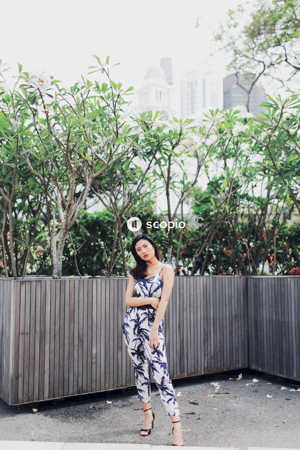 Woman wearing jumpsuit near flower bushes