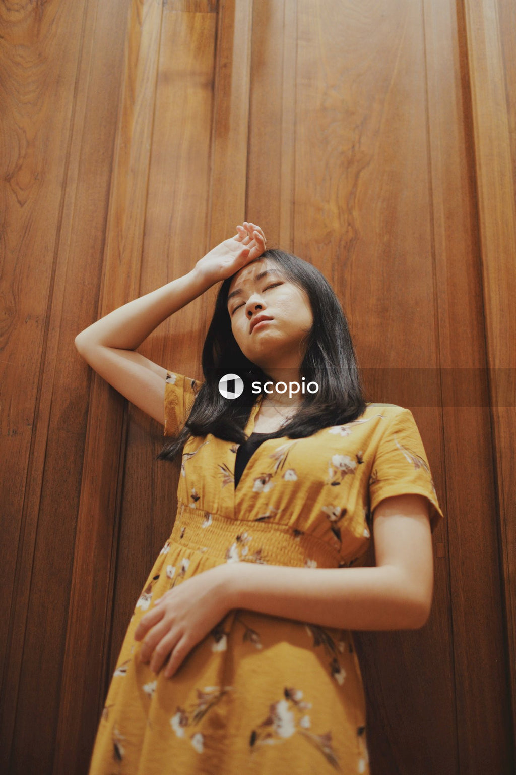 Woman in orange dress standing against wooden wall