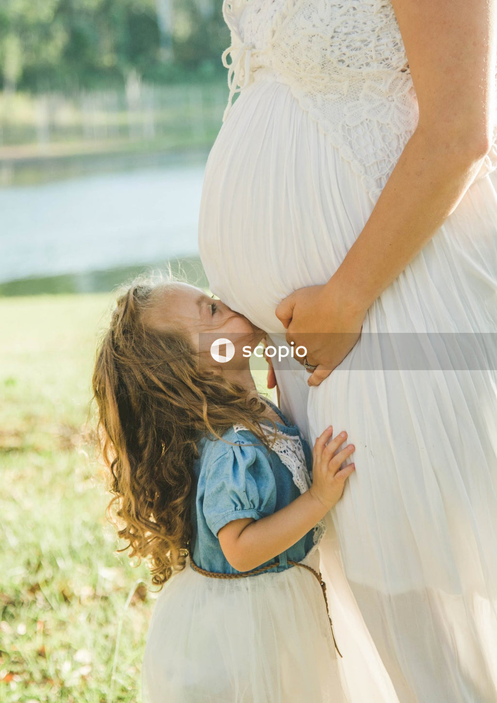Woman in white dress hugging woman in blue denim jacket