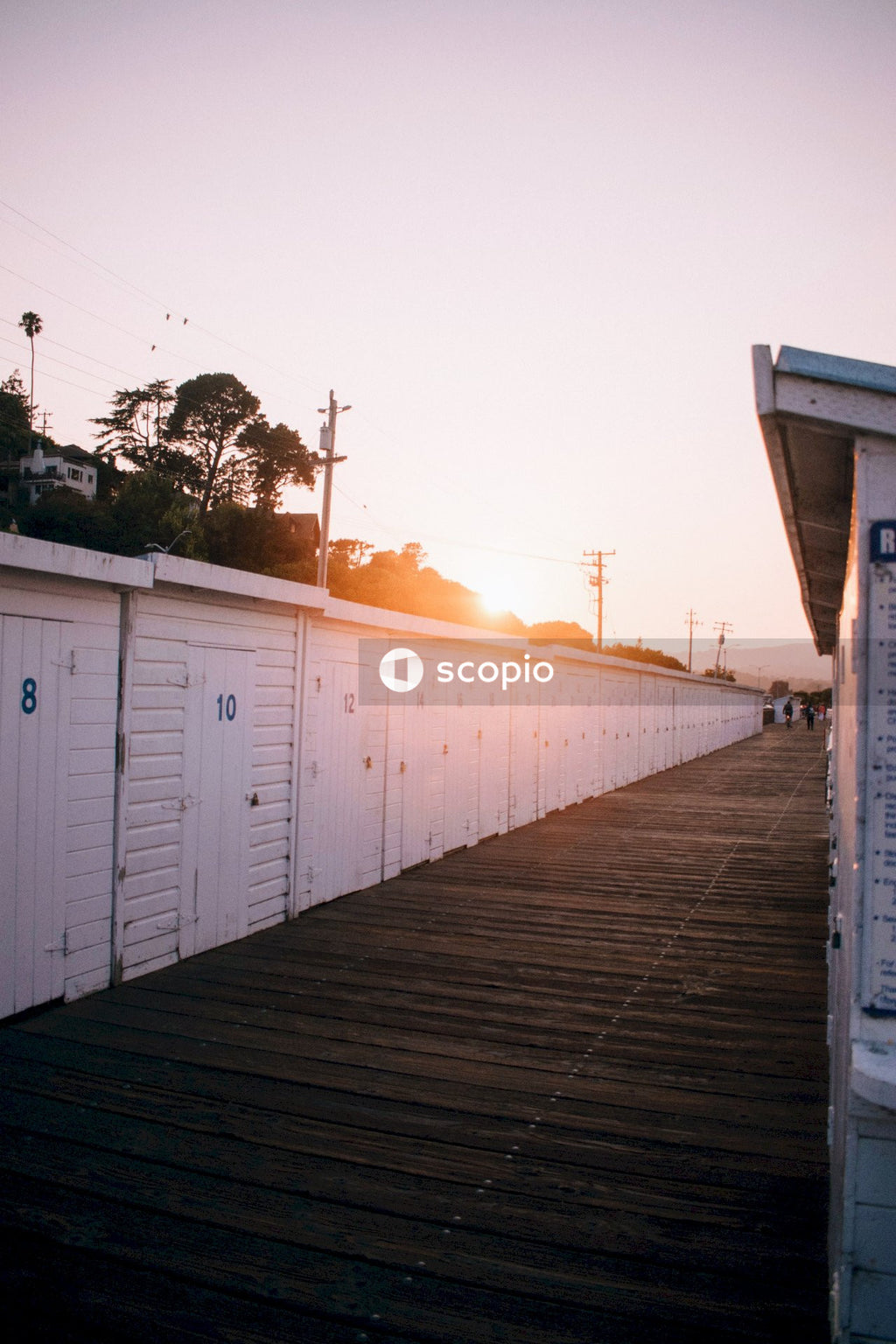 Row of White Sheds Next to Wooden Walkway at Sunset