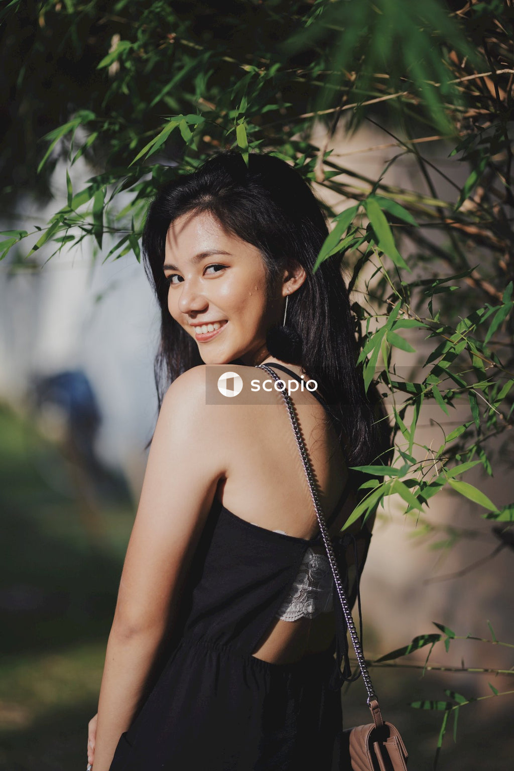Woman in dark dress posing near flowers bushes