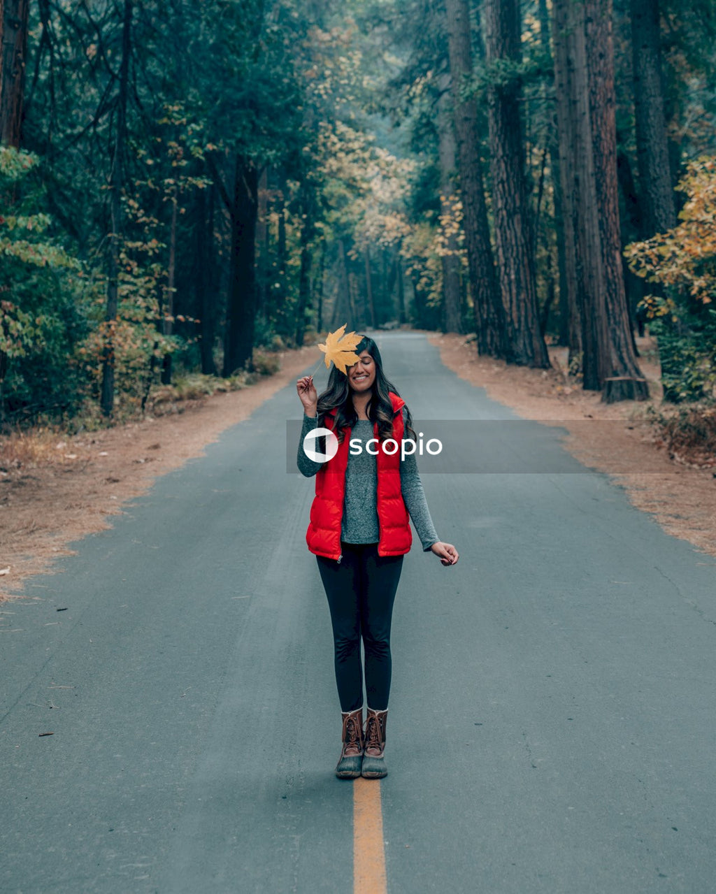 Woman in red coat standing in the middle of the road between trees