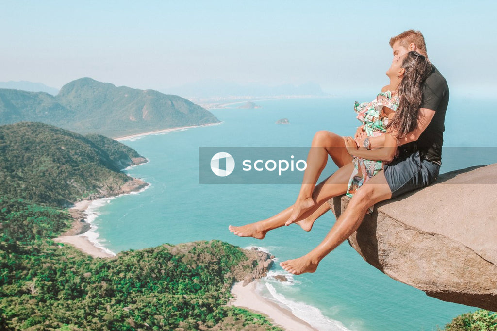 Man and woman sitting at the edge of cliff above the coast