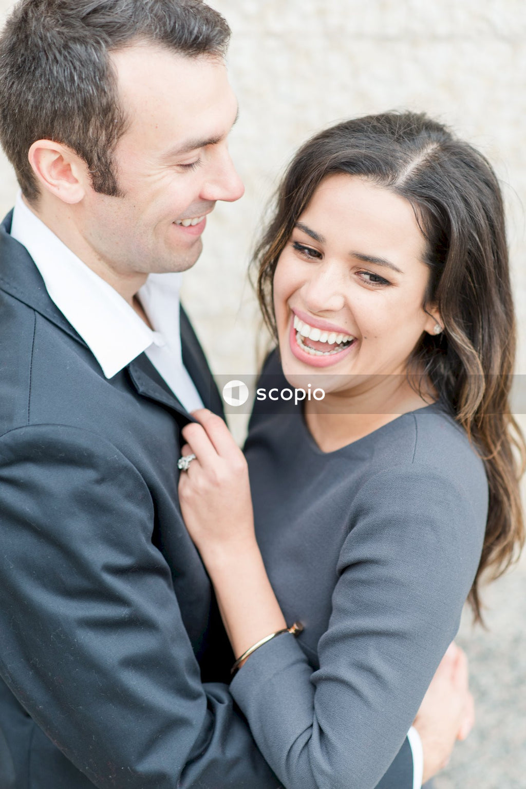 Man in black suit jacket hugging woman in white dress