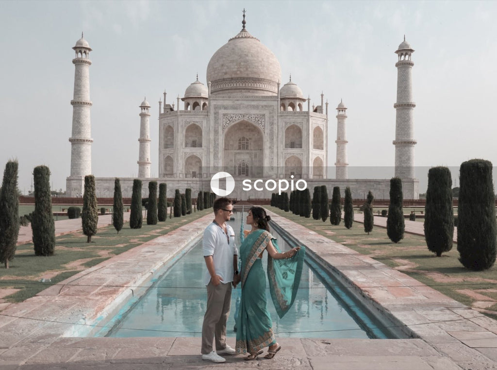 Woman in blue sari and blonde man standing against Taj mahal in Agra, India